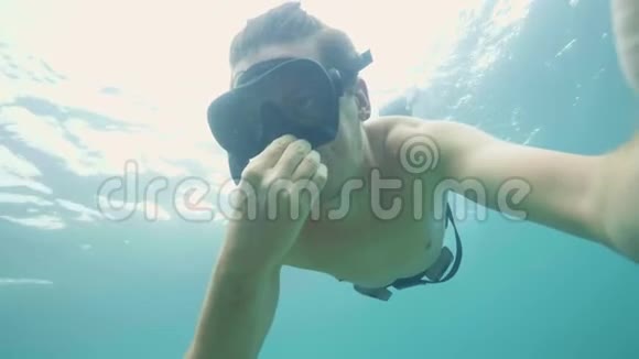 年轻男子吹浮潜面罩以平衡耳朵压力在海上潜水男子拍摄自拍视频视频的预览图