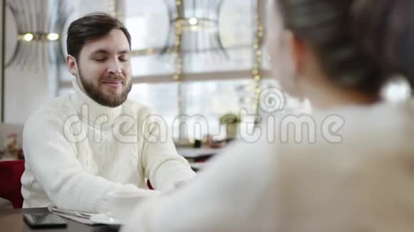 快乐的年轻人在餐馆餐桌旁牵着她的手和女友说话视频的预览图
