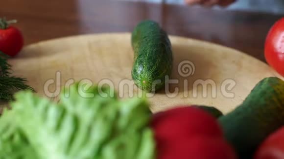 一个女人的特写用刀切成两半把新鲜的黄瓜放在切割板上视频的预览图