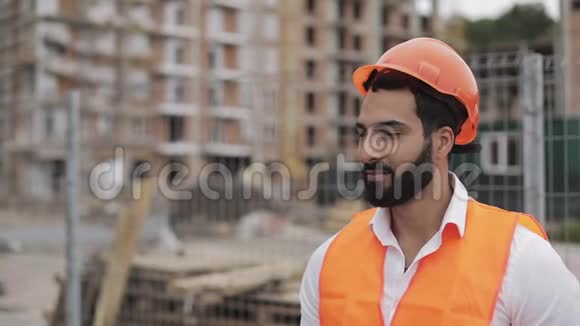 施工工人戴着橙色头盔对着镜头微笑的肖像建筑工人站在视频的预览图