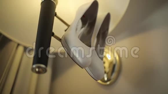 白色的鞋子挂在灯上灯光照在墙上微距拍摄滑翔道上视频的预览图