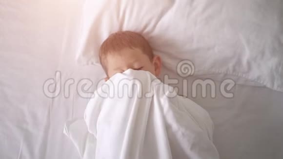 一个小男孩在床上打哈欠和伸展的俯视图视频的预览图