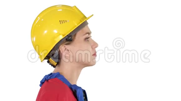 年轻的女工程师带着黄色的安全帽在白色的背景上行走和微笑视频的预览图