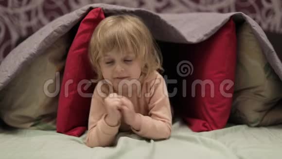 小女孩躲在床上的毯子和枕头下面藏匿地点的概念视频的预览图