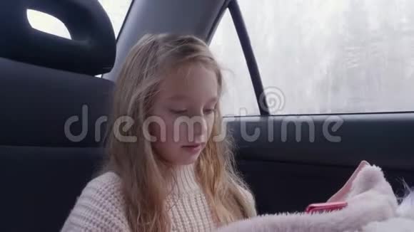 可爱的年轻女孩留着长发开车旅行使用智能手机视频的预览图