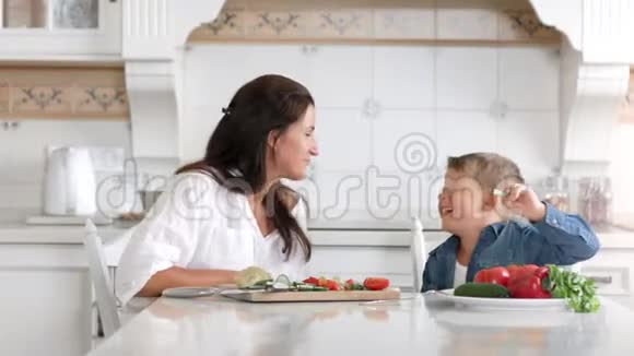 中镜头快乐的妈妈和小可爱的儿子在厨房做饭的时候玩得很开心视频的预览图