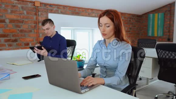 漂亮的女办公室职员在她的笔记本电脑上工作而她的男同事则使用计算器视频的预览图
