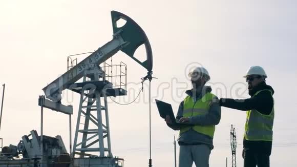 工程师们在油田工作站在油塔附近产油行业理念视频的预览图