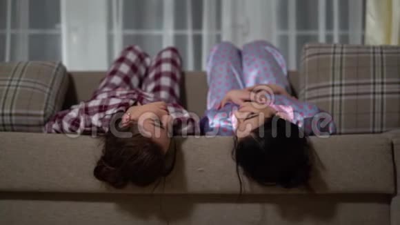两个漂亮的双胞胎姐妹穿着睡衣在房子里的沙发上休息关系姐妹视频的预览图