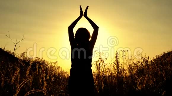 女孩在阳光明媚的日落背景下从事瑜伽和冥想她站着慢慢地连接视频的预览图