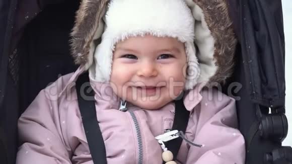 小女孩微笑着坐在雪橇婴儿车上冬雪日冬装4k视频的预览图