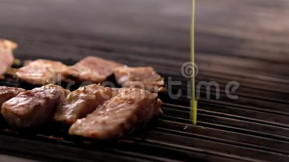 移动摄像机滑块显示鱼片的烹饪过程近距离观看厨师在热烤的外科医生切片上倒入橄榄油视频的预览图