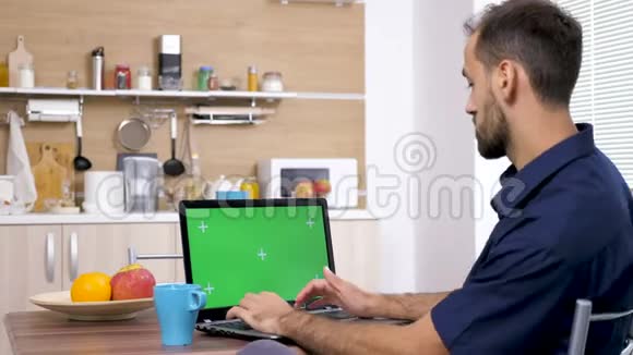 男人在厨房的餐桌上喝着咖啡在电脑上打字视频的预览图