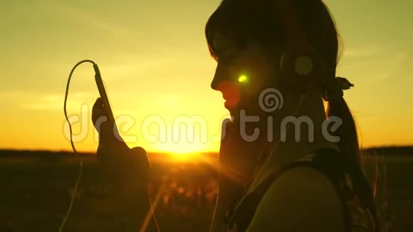女孩在温暖的阳光下旅行和听音乐少女听音乐看日落快乐女孩视频的预览图