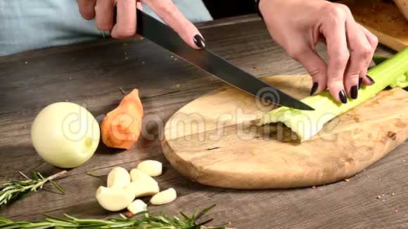 女厨师将切好的芹菜切在切好的蔬菜旁边的木切割板上的概念视频的预览图