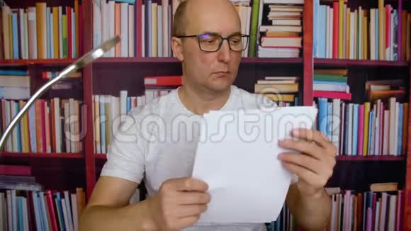 成人商人在书架背景上阅读家庭办公室的文件视频的预览图
