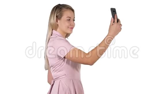 年轻漂亮的女人在白色背景下在手机上自拍视频的预览图