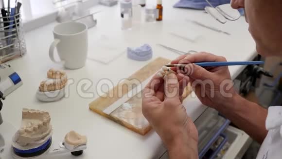 牙科技师在种植生产实验室在人造牙齿上涂白色油漆视频的预览图
