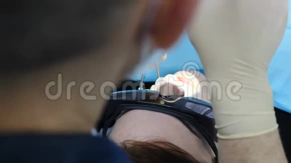 女医生在她的柜子里治疗女病人在牙科办公室的一个年轻女人的特写镜头牙医使用镜子视频的预览图