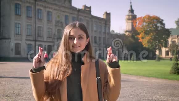 美丽的白种人女性站直了用交叉的手指祈求好运户外古老视频的预览图