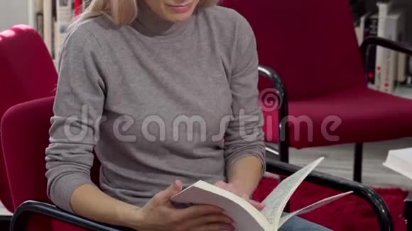 在大学图书馆看书的时候一个迷人的女人对着镜头微笑视频的预览图
