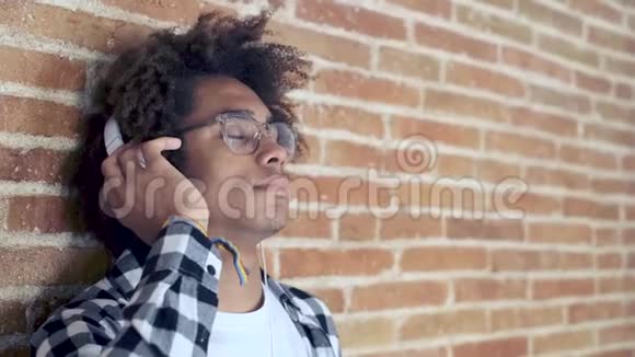 美国黑人年轻人在家里靠在石头墙上听音乐心情轻松视频的预览图