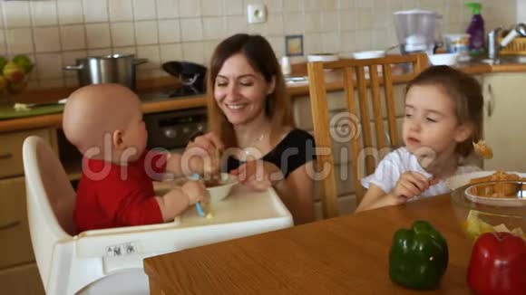 强壮的孩子在厨房的高椅里吃饭妈妈不能他拿勺子儿童健康营养视频的预览图