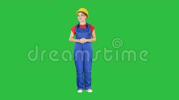 年轻的微笑工人女主持人从绿色屏幕的两边按下想象中的按钮色度键视频的预览图