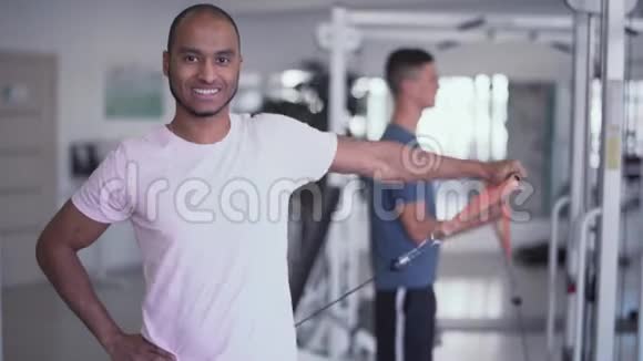 快乐的男人在健身房里一只手轻松地增加体重视频的预览图
