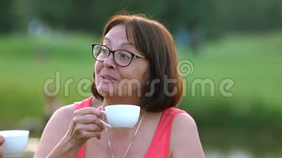 把在户外喝茶的漂亮女人关起来视频的预览图
