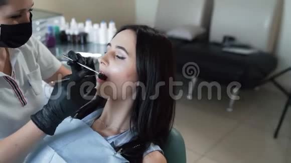 牙医用牙科工具检查病人牙齿动作缓慢牙医办公室的女人视频的预览图