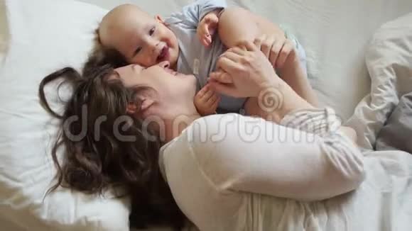妈妈爱宝宝和妈妈早上在床上拥抱和微笑家庭幸福妈妈日子产妇概念视频的预览图