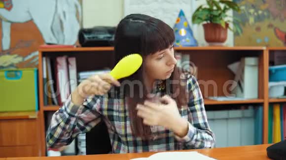 一位年轻的女老师正在梳理她的黑发坐在办公室里视频的预览图