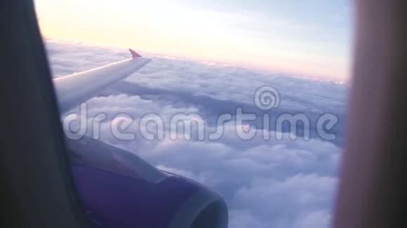 清晨日出时从飞行的飞机窗翼和白云中观看多云天空的空中风景日落视频的预览图