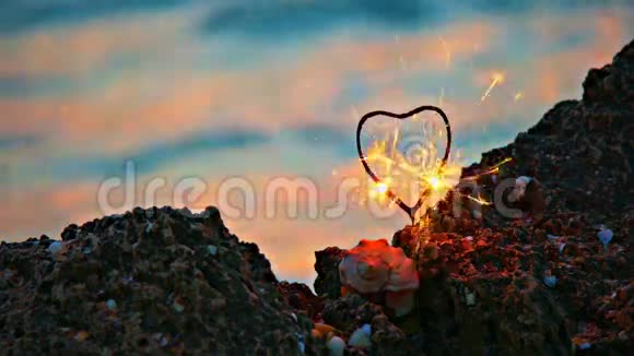 在缓慢移动的海水前岩石海岸上的心形火花表面有温暖的日落光点视频的预览图