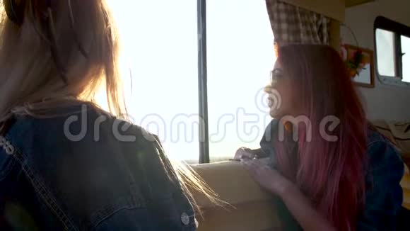 两个穿着夕阳的女孩望着自动拖车的窗外视频的预览图