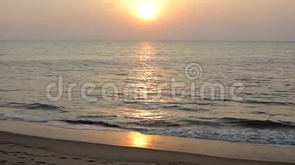 沙滩上的沙滩上有一艘船在大海里傍晚夕阳下有一条阳光明媚的小路视频的预览图
