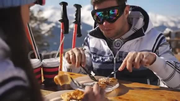 在滑雪场午休年轻夫妇在山上的户外餐馆吃午饭并与每个人交流视频的预览图