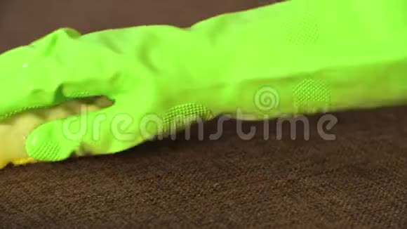 戴绿色手套的女人用黄色海绵清洁沙发视频的预览图