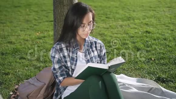 亚洲美国妇女看书的正面景色坐在户外视频的预览图
