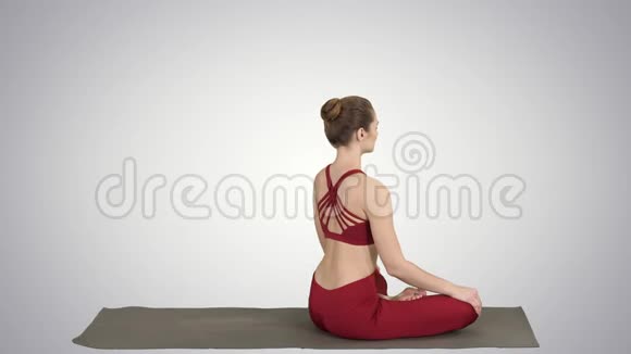 运动的女人练习瑜伽莲花姿势转向相机在梯度背景上微笑视频的预览图
