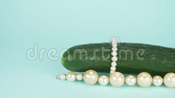 时尚艺术美食设计新鲜黄瓜配一串珍珠蓝色背景视频的预览图