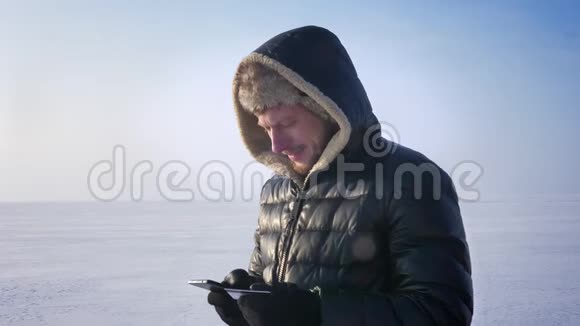 商人站在冰冻的湖面上用信用卡和智能手机进行交易转向相机和微笑视频的预览图