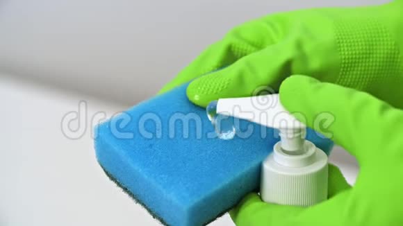 将绿色手套推式分配器和液体洗涤剂挤到蓝色海绵上视频的预览图