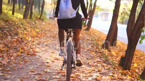 穆斯林妇女戴着头巾背着背包骑着自行车在秋天公园的后景中慢悠悠地视频的预览图