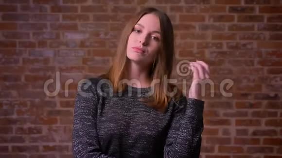 金吉尔年轻的女人在镜头前调情并在一个金砖背景上的手指上扭动她的头发视频的预览图