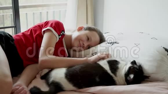 可爱的少女和她的猫玩耍在床上大笑视频的预览图