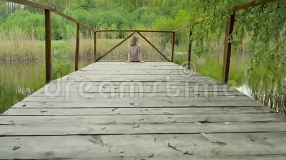 坐在河边的一座木桥上的少女视频的预览图