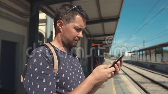 白天站在火车站的游客正在用手机打短信视频的预览图