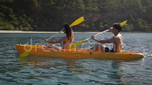 令人惊叹的侧景慢动作快乐的年轻夫妇在热带岛屿附近划独木舟视频的预览图